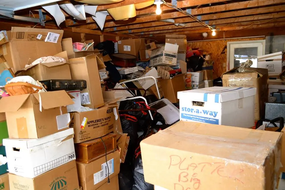 A cluttered garage filled with boxes, tools, equipment, and bulky items